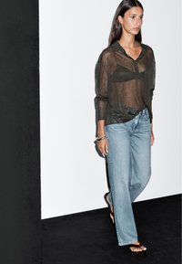 Durchsichtige dunkelgrüne Knopfbluse, hellblaue weite Jeans und schwarze Sandalen. Einfaches Design mit lockerer Passform und minimalem Hardware.