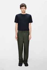 Čierne krátke tričko s krátkym rukávom, skombinované s tmavozelenými nohavicami s elastickým pásom. Hladká látka, voľný strih a nariasené manžety na nohaviciach.