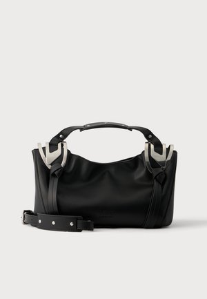 Bolso de mano de piel negra con asa corta superior, hebillas en tono plateado y correa de hombro desmontable, sobre un fondo liso y claro.