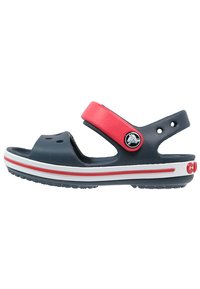 Sandali sintetici blu con una fascia rossa e dettagli bianchi. Presentano fori per la ventilazione, una fascia regolabile e una suola texturizzata per una migliore aderenza.