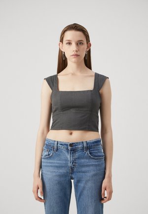 Top court gris avec décolleté carré et design ajusté, associé à un jean taille haute léger en bleu. Tissu lisse et détails minimalistes.