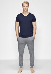 Navy V-neck T-shirt paired with light gray slim-fit sweatpants. Both garments feature soft fabric, and the pants have elasticized cuffs.