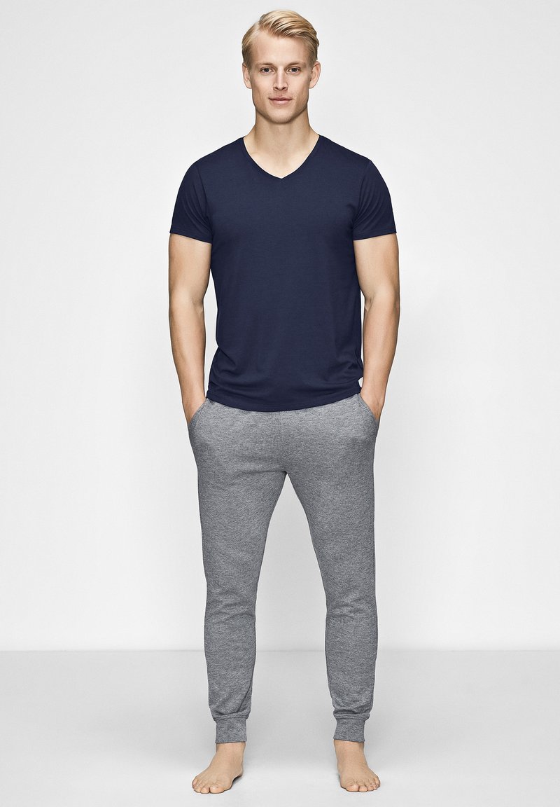 Navy V-neck T-shirt paired with light gray slim-fit sweatpants. Both garments feature soft fabric, and the pants have elasticized cuffs.