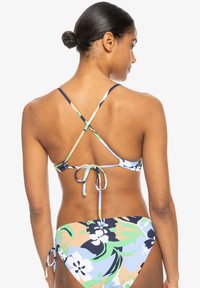 Conjunto de bikini floral con tirantes cruzados. Presenta un patrón floral multicolor en tonos azules, verdes y neutros. Se ata en la parte posterior con un ajuste ajustable.
