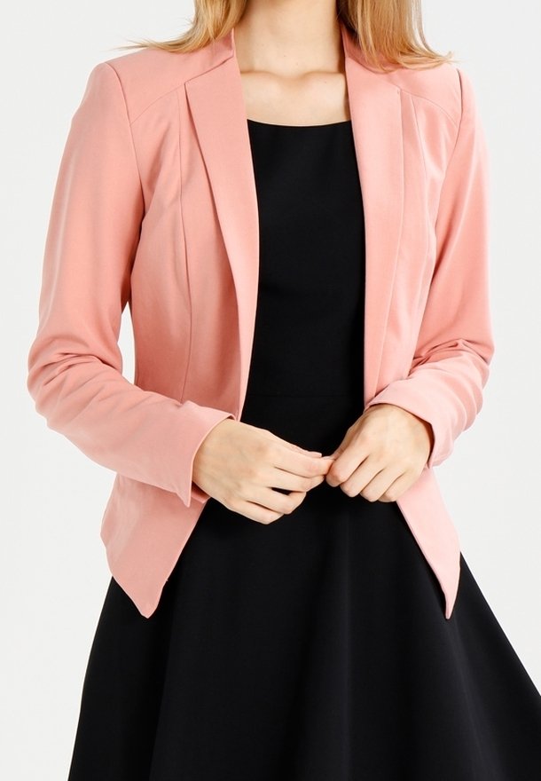 Blazer rose pâle en tissu lisse avec une coupe ajustée, col à revers crantés et fermeture par un bouton, assorti à une robe noire.