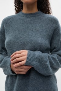 Maglione di lana grigio con scollo rotondo, polsini a coste e una finitura morbida e strutturata. Il design è rilassato, con maniche lunghe.