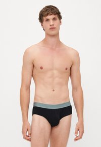 Zwarte onderbroek met een zachte, grijze elastische tailleband. Soepele textuur, laaghangend ontwerp en minimalistische stijl. Geen patronen of accenten zichtbaar.