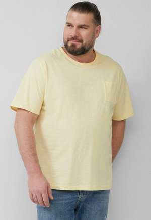 Helles gelbes T-Shirt mit kurzen Ärmeln aus weichem Material, mit Rundhalsausschnitt und einer kleinen Tasche auf der linken Brust.