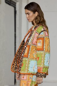 Gequilte jas met een patchworkdesign in helder oranje, blauw en groen, met accenten van luipaardprint en verschillende diertjespatronen.