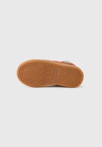 Gummisåle med et geometrisk mønster, med en oransje overdel med en teksturert finish og et sølvfargeaccent. Robust og fleksibel design.