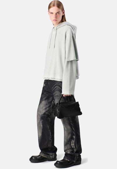 Jasnozielona, oversize'owa bluza z kapturem, o warstwowym designie. Czarne, teksturowane spodnie o szerokich nogawkach. Czarna torebka z falującą górą. Czarne buty.
