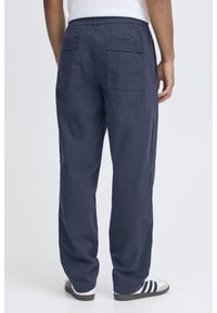 Granatowe spodnie cargo z elastycznym paskiem w talii, dwoma tylnymi kieszeniami i luźnym krojem. Materiał wydaje się lekki o gładkiej fakturze.