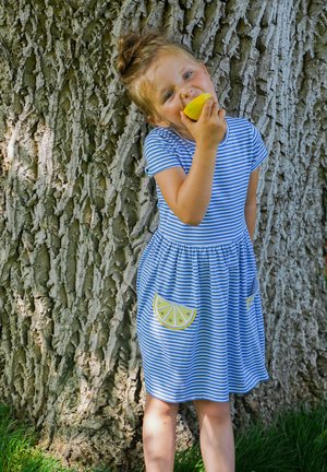 Blau-weiß gestreiftes Kleid mit kurzen Ärmeln, geraffter Taille und Taschen mit Zitronenmotiv. Hergestellt aus leichtem Stoff, getragen mit einer Zitrone.