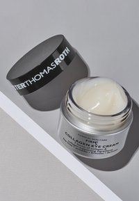 Silverfärgad burk med kollagenögonkräm, svart lock, innehållande en slät vit kräm, märkt med produktnamn och användningsanvisningar.