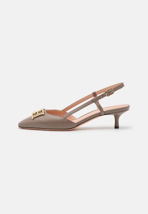 Escarpin slingback en cuir taupe à petit talon kitten, bout pointu et boucle décorative dorée devant, avec bride de cheville réglable.