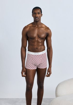 Ανδρικά εσώρουχα Calvin Klein σε λευκό με κόκκινα γεωμετρικά σχέδια, ελαστική μέση με λογότυπο, εφαρμοστό σχέδιο και απαλή υφή.