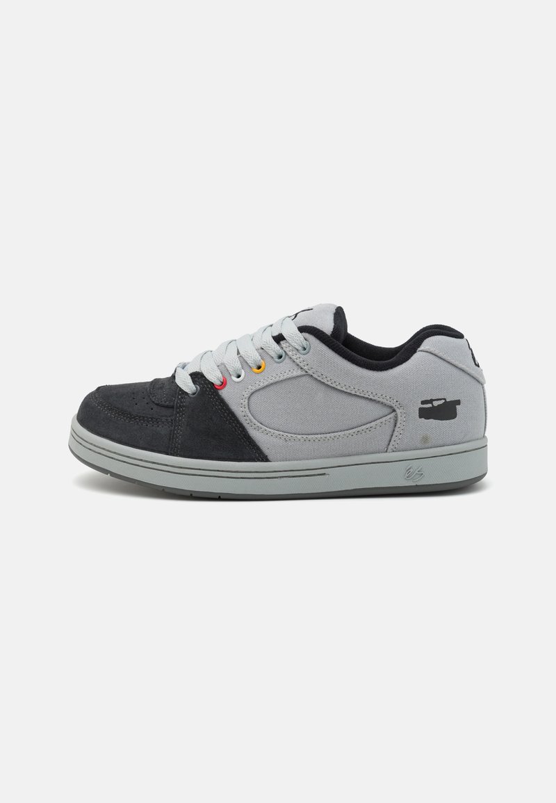 Szare i czarne sneakersy z materiałów zamszowych i kanwasowych, okrągły nosek, płaska gumowa podeszwa, kolorowe oczka i detal logo na pięcie.