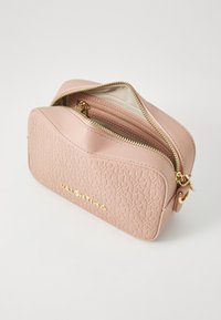 Ροδοκόκκινη συνθετική δερμάτινη τσάντα καλλυντικών με υφή και χρυσές λεπτομέρειες, διαθέτοντας κλείσιμο με φερμουάρ και εσωτερική τσέπη με φερμουάρ.