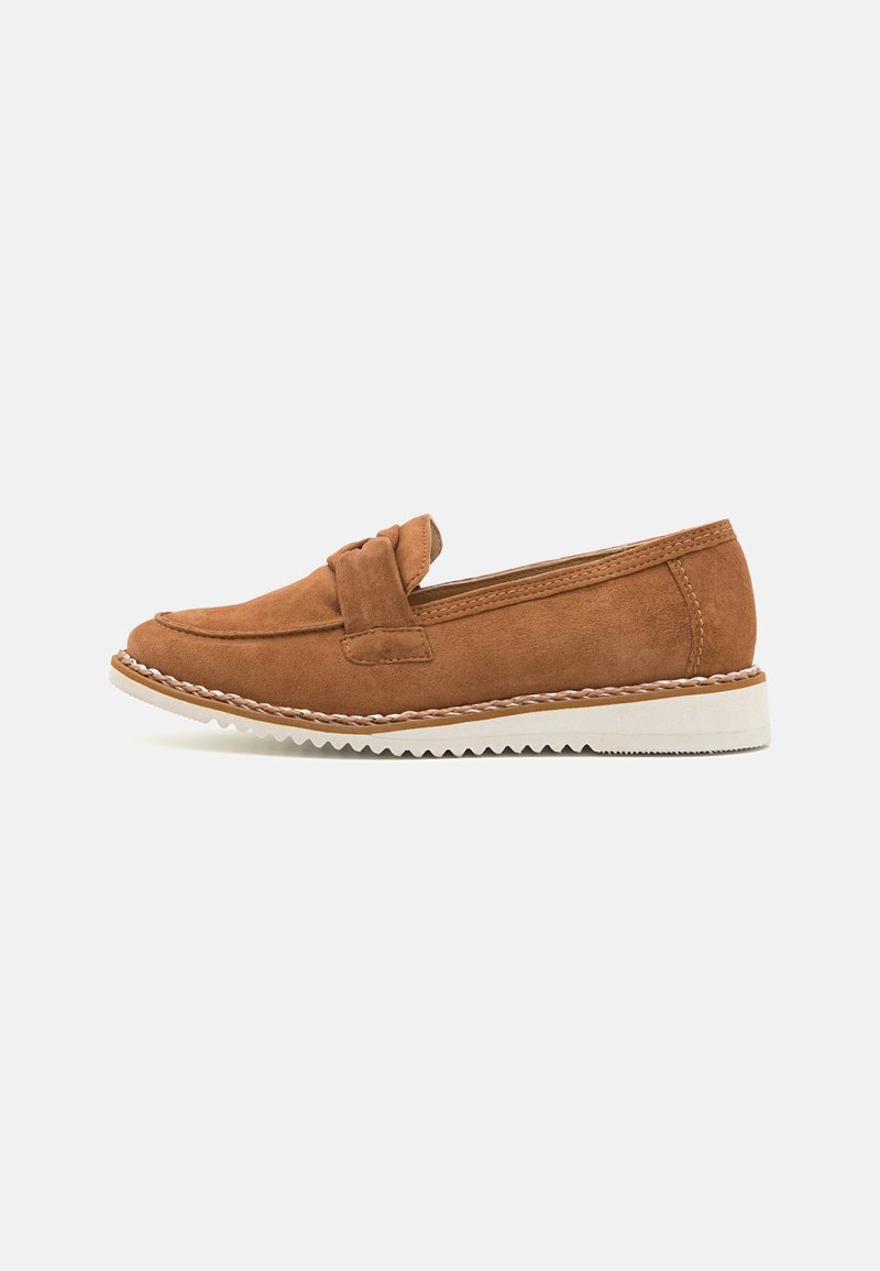 Mocassins en daim marron avec un accent noué, dotés d'une semelle en caoutchouc blanche contrastante et de détails en bordure en zigzag.