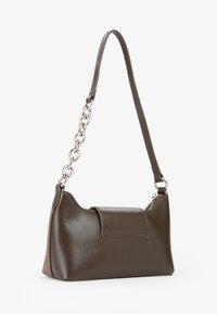 Mała ciemno-brązowa skórzana torebka z krótkim paskiem, ozdobiona srebrnymi ogniwami łańcucha oraz zamknięciem na zamek błyskawiczny u góry.