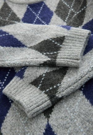 Pelēka vilnas džemperis ar argyle rakstu tumši pelēkā, jūras zila un gaiši zila krāsās. Pārsvarā ir ribotie piedurknes un mīksta tekstūra.