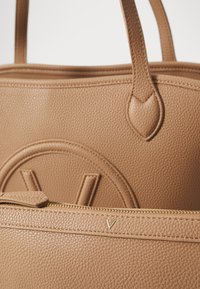 Τσάντα tote σε καφέ δέρμα με λεία υφή, στρογγυλές λαβές και κλειστό τσαντάκι με φερμουάρ σε χρυσή απόχρωση, με ανάγλυφο το γράμμα "V."