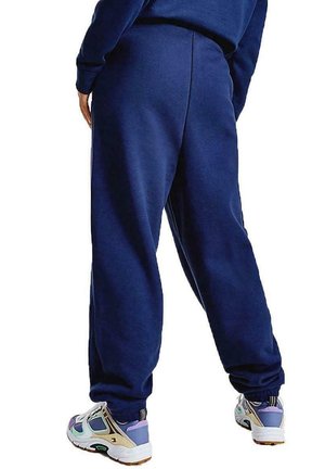 Pantaloni della tuta blu marina con vestibilità rilassata, vita elastica e polsini svasati, abbinati a scarpe da ginnastica multicolori.