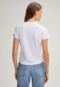 Witte katoen t-shirt met korte mouwen, ronde halslijn en een ontspannen pasvorm, gecombineerd met lichtblauwe denim jeans. Eenvoudig, casual ontwerp.