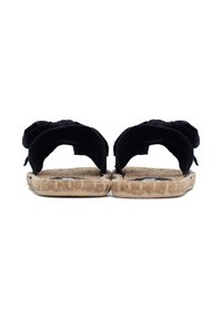 Pantofole in tessuto nero con suola in jute intrecciato. Design aperto sul retro con morbidi dettagli arricciati alle cinghie. Parte inferiore testurizzata per una presa migliore.