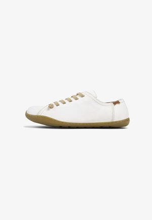 Chaussure décontractée blanche basse avec semelle et lacets marron clair, avec des coutures minimales et une petite étiquette marron près du talon.