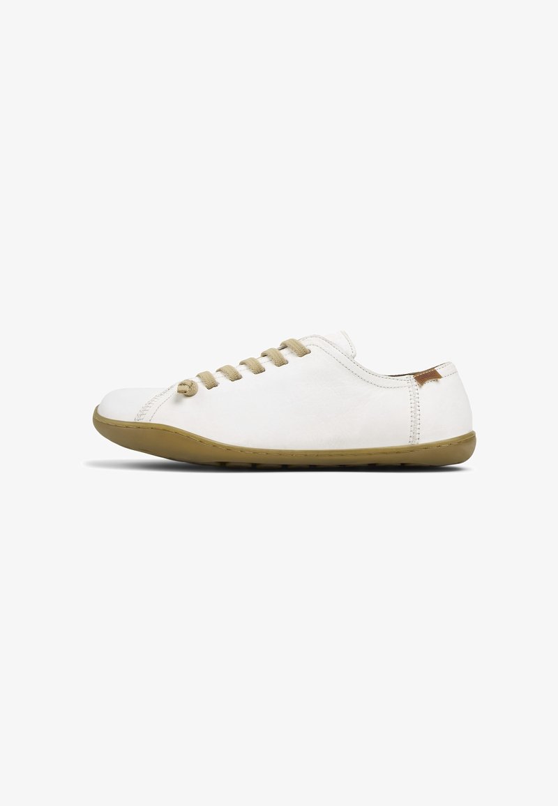 Chaussure décontractée blanche basse avec semelle et lacets marron clair, avec des coutures minimales et une petite étiquette marron près du talon.