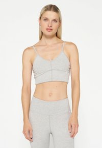 Grå sport BH med tynde stropper, tekstureret stof og cropped design. Har en central søm og logo accent nær kanten.