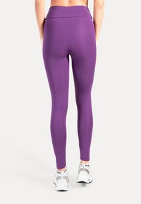 Paars, high-waisted yogalegging van rekbaar materiaal, met een gladde afwerking en een aansluitend ontwerp dat het lichaam vormt.