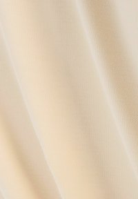 Tissu beige avec une surface douce et texturée, présentant de fines motifs tricotés. Le matériau semble léger et flexible.
