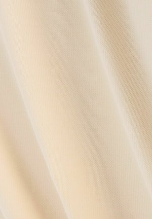 Tela beige con una superficie suave y texturizada, que muestra finos patrones de punto. El material parece ligero y flexible.