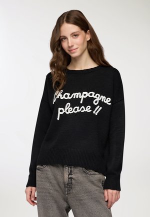 Maglione nero a maglia con testo cursivo bianco "champagne please" sul davanti. Vestibilità ampia con polsini e orlo a costine; texture morbida.