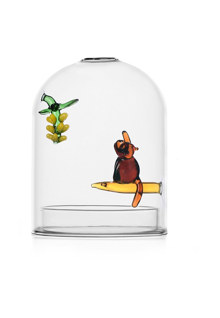 Glazen cloche met een duidelijke koepel, met kleurrijke glazen figuren: een bruine aap op een gele skateboard en een groene plant met gele bladeren.