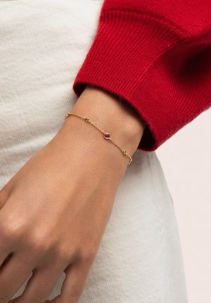 Pulsera de cadena de oro con piedras preciosas de colores, incluyendo rosa, verde y azul, presenta un diseño delicado y eslabones intrincados.