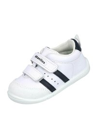 Zapatilla deportiva blanca con franjas negras, hecha de material sintético. Presenta correas de Velcro, perforaciones para ventilación y una suela de goma.
