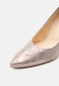 Ασημένιο γυναικείο παπούτσι με μύτη σε γωνία, επίπεδο, με απαλή σουέτ υφή και μπεζ εσωτερική επένδυση σε λευκό φόντο.