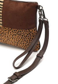 Smeđa torba od umjetne kože s donjim dijelom u bež točkicama, prugastim materijalom na vrhu i odvojivim remenom za rame s metalnim detaljima.