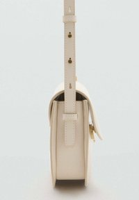 Borsa a tracolla beige in pelle vista di lato, che mostra la tracolla regolabile con dettagli in oro e chiusura a pattina.