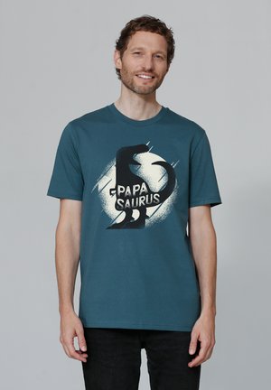 Teal korte mouw t-shirt van katoen met een grote zwarte dino graphic en de tekst "PAPA SAURUS" in vetgedrukte witte letters.