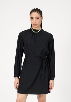Robe noire à manches longues avec col montant, taille ajustable par cordon et poignets élastiques. Elle présente une texture lisse et une coupe décontractée.