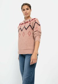 Rosa Strickpullover mit Diamantmustern und Zickzackakzenten in Dunkelrot und Marineblau. Verfügt über lange Ärmel und gerippten Saum. Getragen mit blauen Jeans.