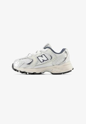 White athletic shoe with mesh panels, round toe, and cushioned sole. Features a blue accent and a prominent "N" logo on the side.