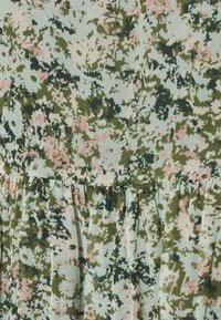 Närbild av ljusblått tyg med rosa, vita och gröna blommönster samt rynkade sömmar.