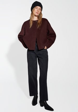 Burgundy cropped cardigan with dropped shoulders and single button closure, paired with straight black jeans and black ankle boots.