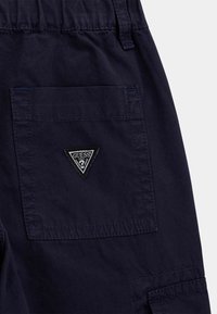 Navyblaue Cargo-Shorts aus Baumwolle mit strukturiertem Finish, ausgestattet mit einem dreieckigen schwarzen 'Guess'-Logo und mehreren Taschen.