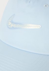 Svetlomodrá baseballová čiapka s priesvitným Nike swoosh logom vyplneným perleťovými korálkami vyšitými na prednej strane.